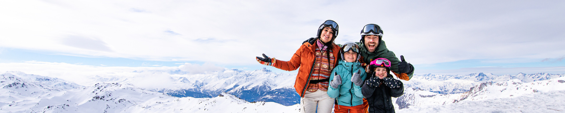 Une famille au ski qui sourient avec les montagnes en arrière-plan