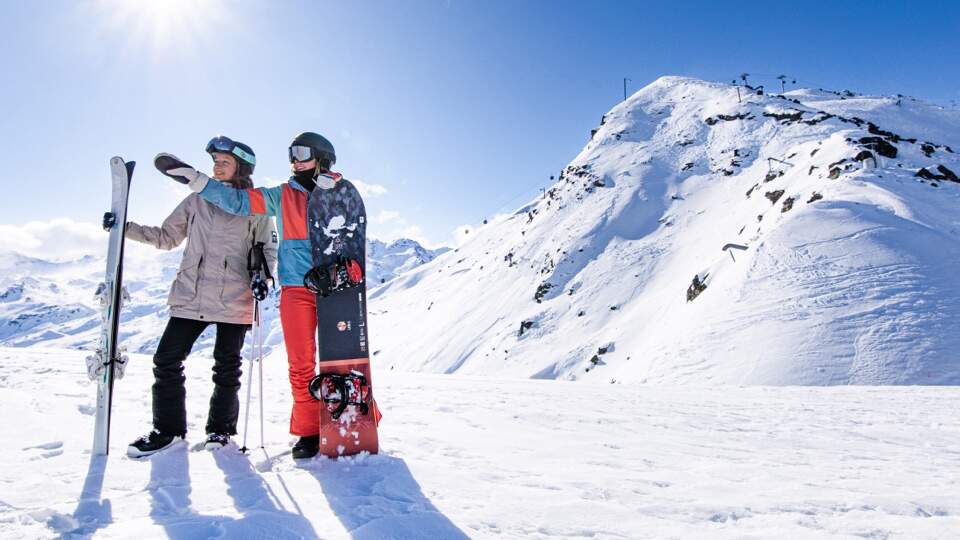 2 snowboarders contemplant les montagnes ensoleillées