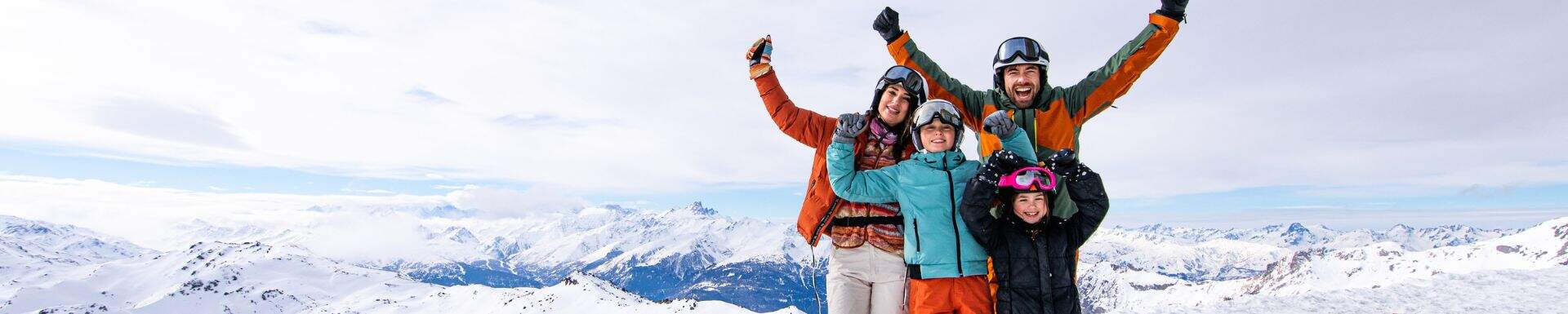 Une famille au ski levant les bras