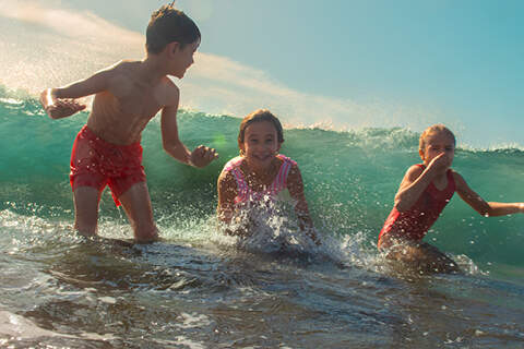 3 enfants prenant la vague en pleine mer