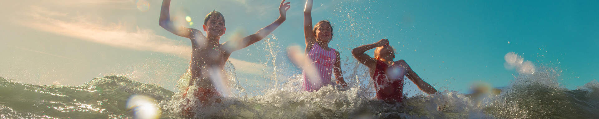 3 enfants prenant la vague en pleine mer