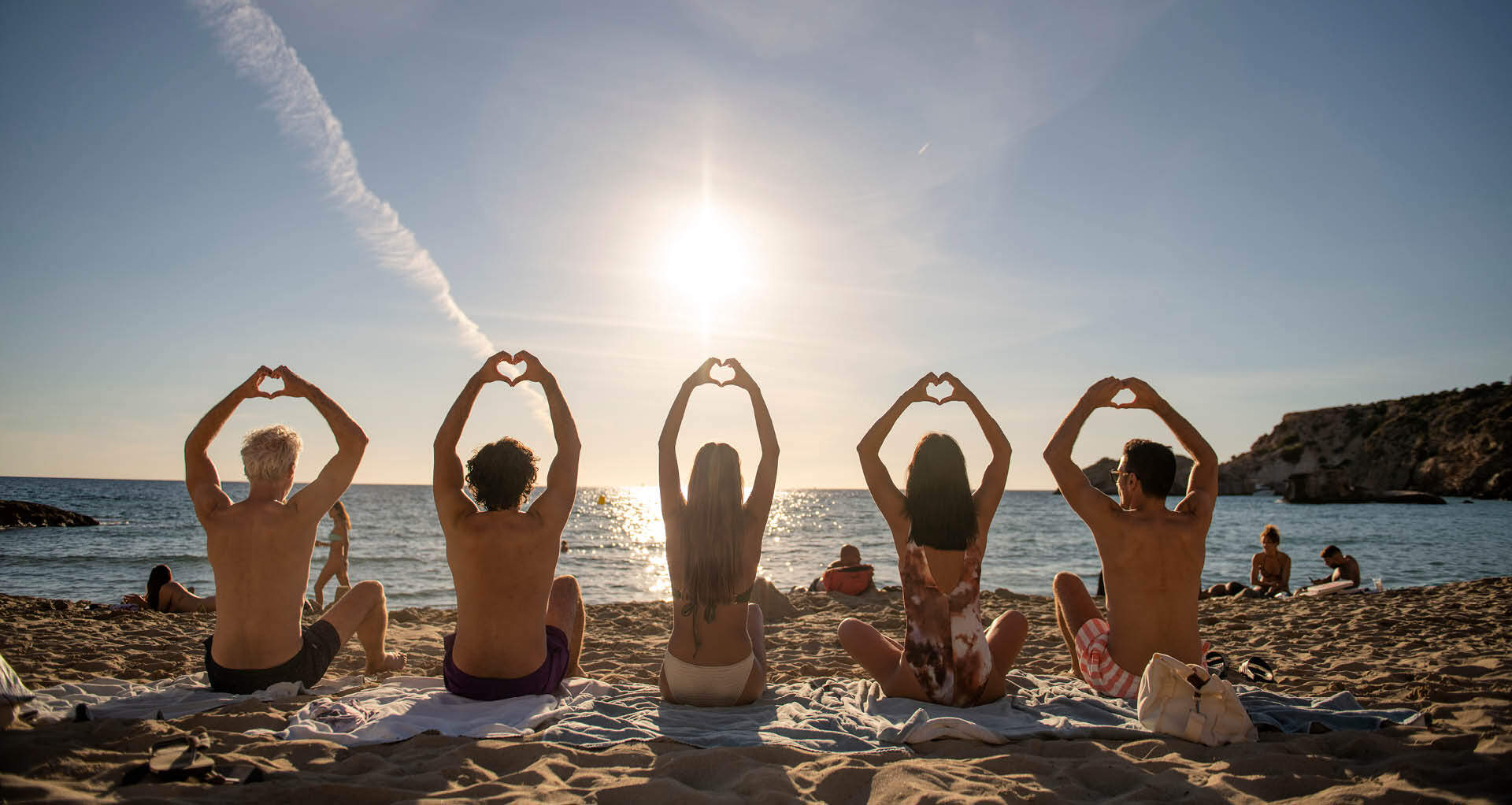 Famille faisant le signe du coeur lors d'un coucher de soleil à la plage