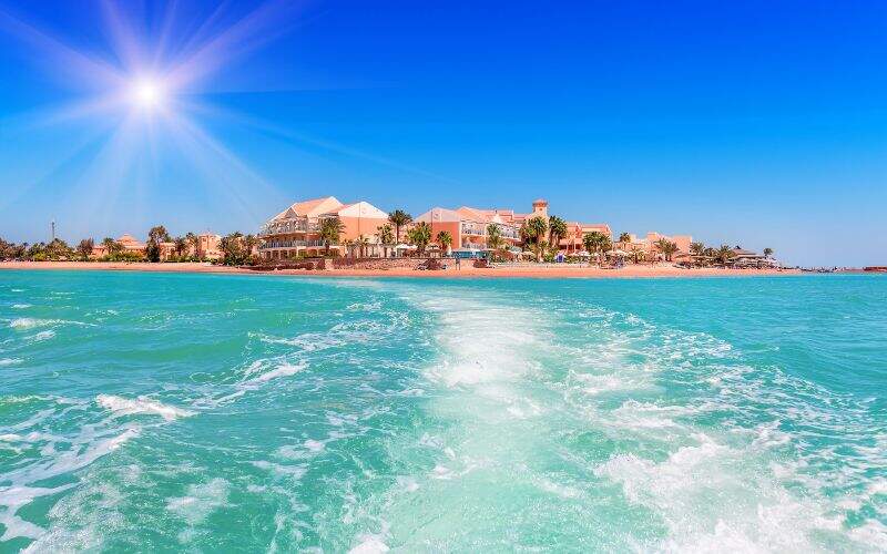 Vue depuis mer aux eaux claires sur rivage avec habitations et verdure