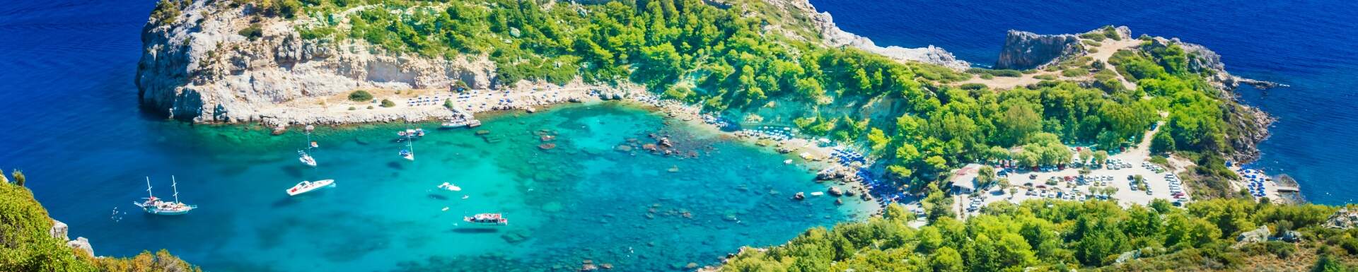 Vue d'en haut mer cristalline et bateaux entourée de falaises verdoyantes, Rhodes, Grèce