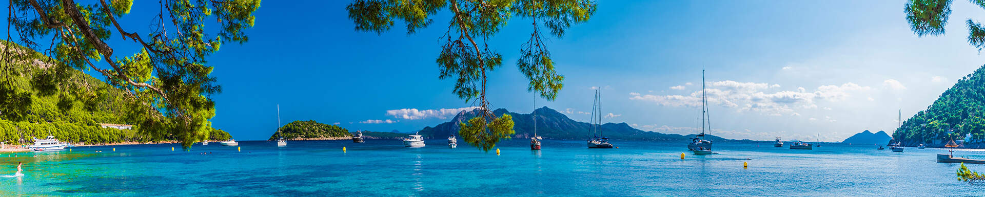 Plage aux eaux cristallines avec bateaux entourée de montagnes verodyantes, Espagne