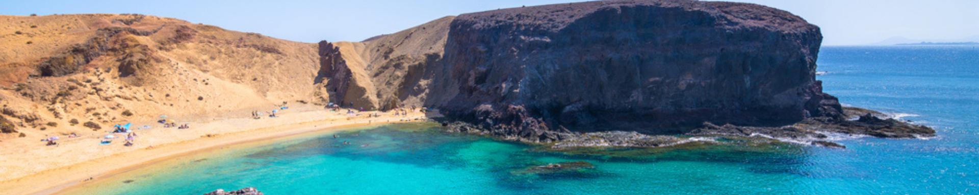 Plage de sable doré et eaux cristallines avec rocher imposant, Lanzarote, Espagne