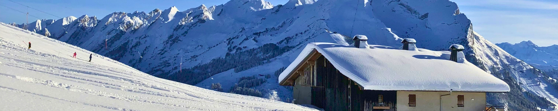 Un chalet au pied des pistes de ski avec la montagne en arrière-plan