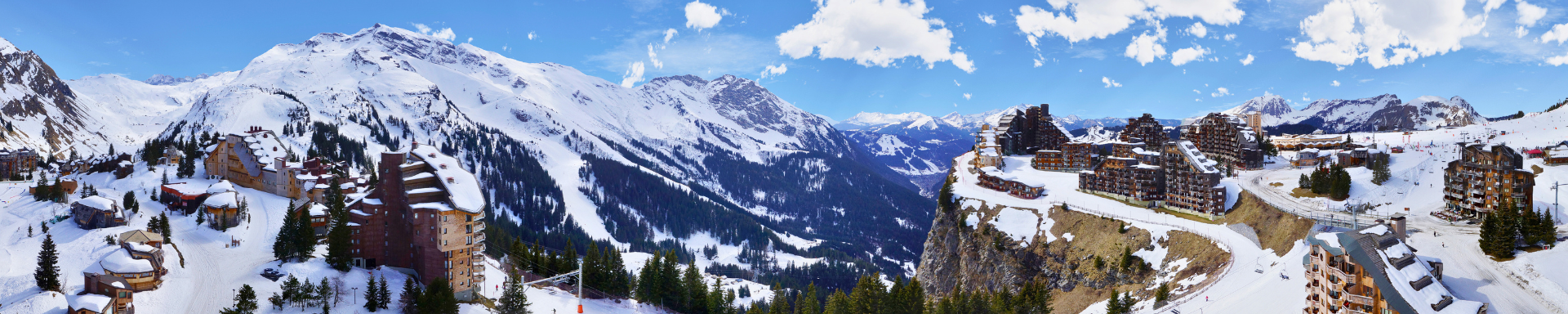 Vue panoramique sur une station de ski enneigée avec des résidences au pied des pistes
