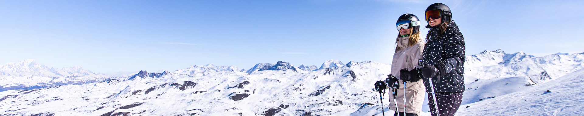 Deux skieuses regardant la vue sur les montagnes enneigées