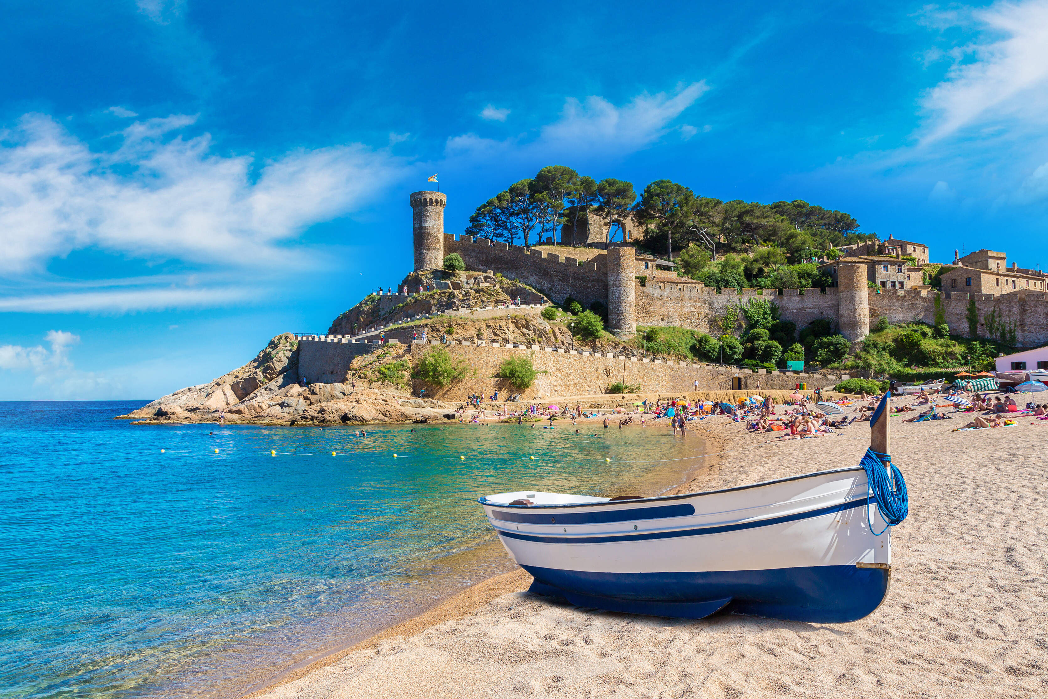 Petite barque bleue et blanche en bord de plage avec en arrière plan, un phare et verdure