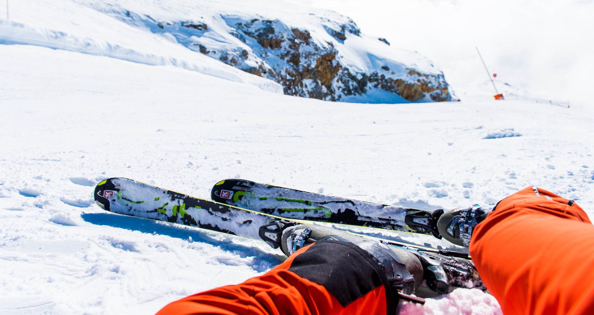 Personne assis dans la neige portant une combinaison orange