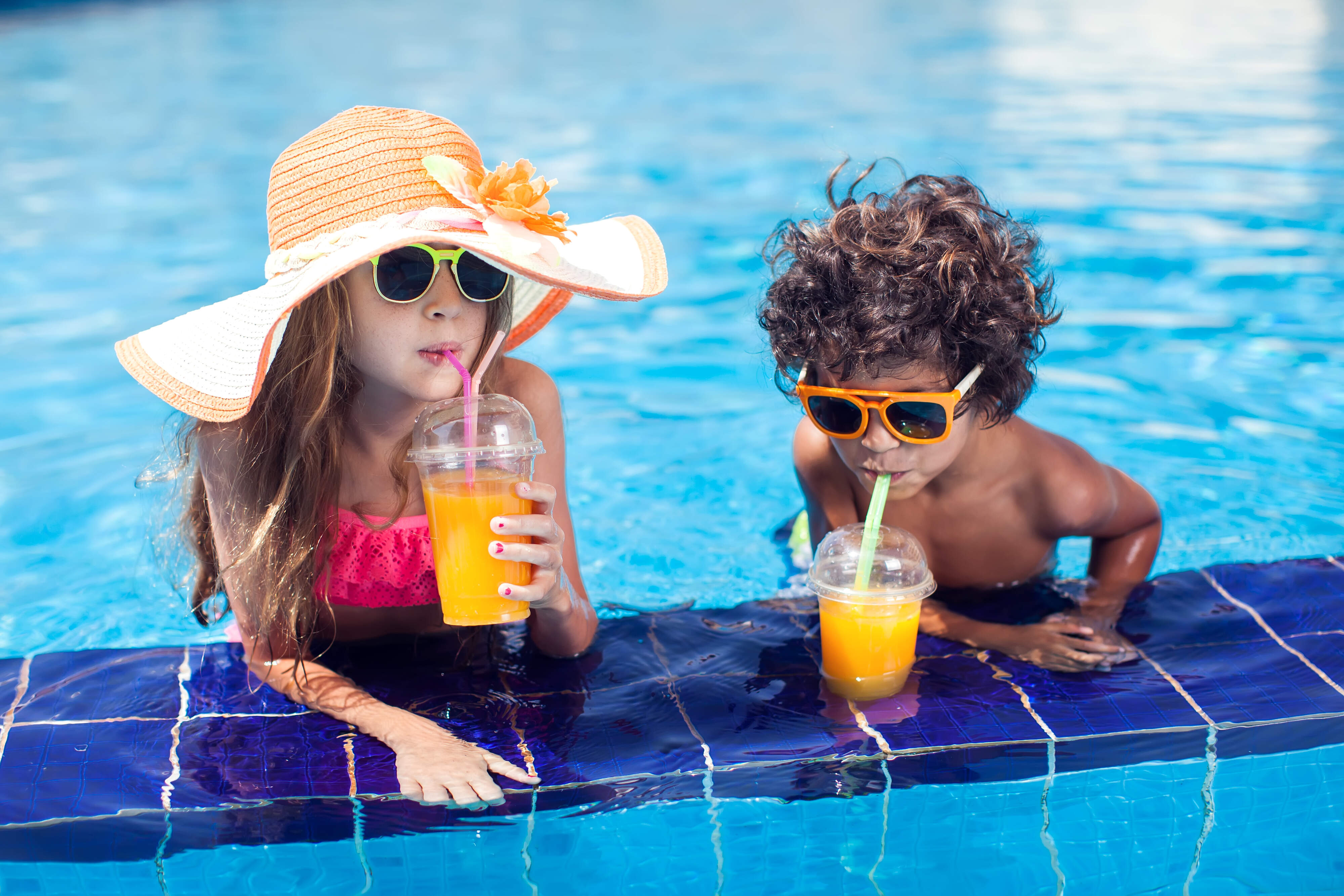 Enfants qui sirotent une boisson au bord de la piscine