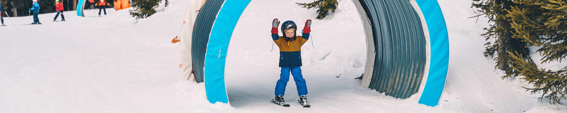 Un enfant sur les pistes de ski qui lève les bras en l'air